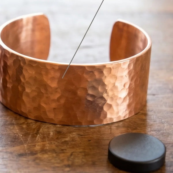 A magnet held to a solid copper cuff, not sticking